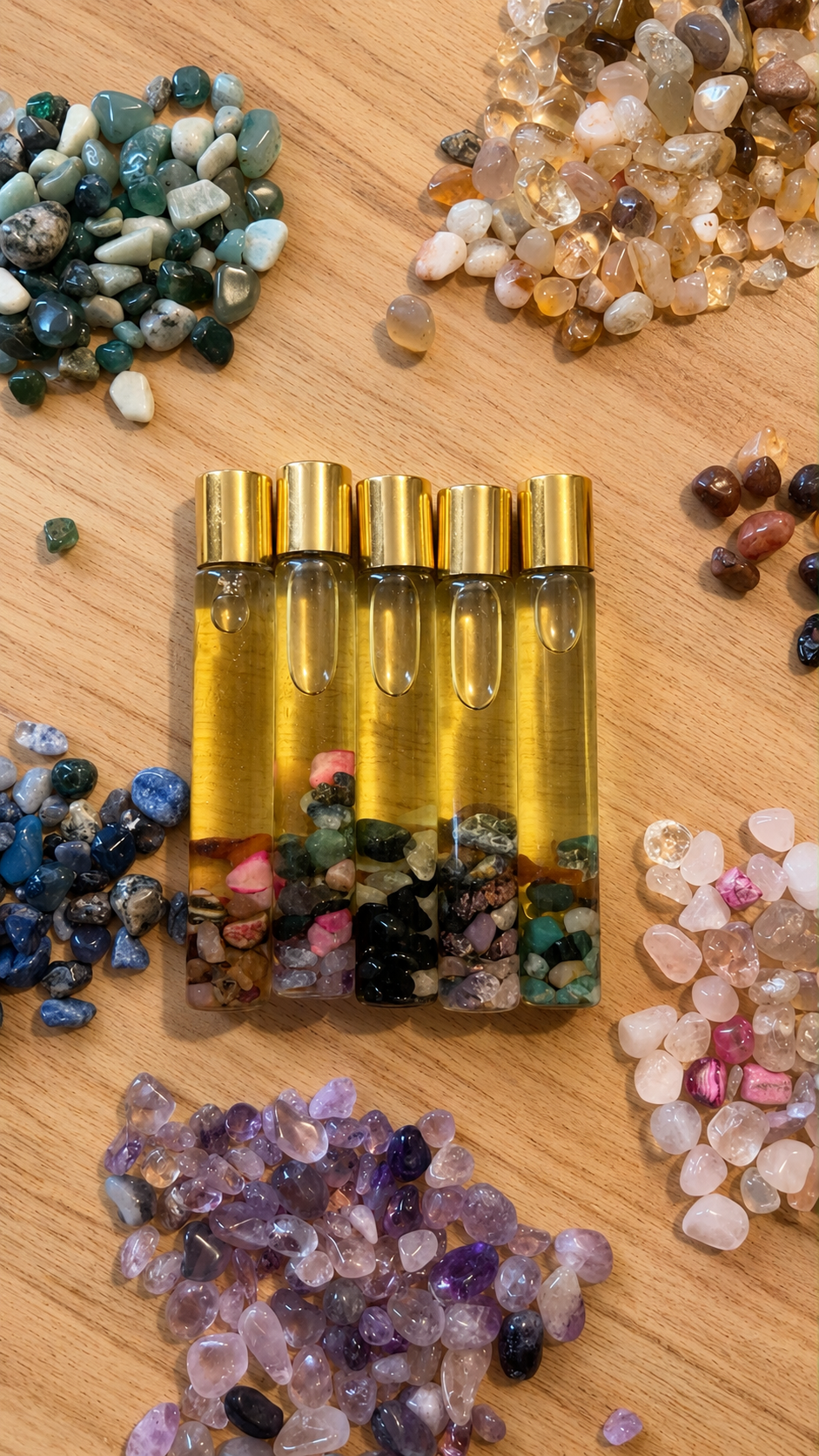 Os cinco frascos do ritual Voltar para Si ao lado de pilhas de cristais naturais separados por tipo, durante a seleção manual de cada pedra.
